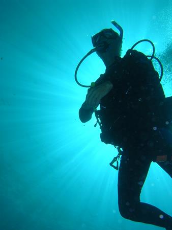 Silhouetted diver ascending